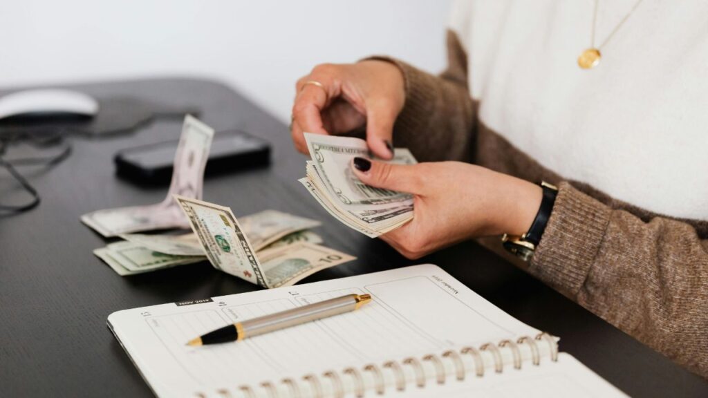 Counting money on a desk representing a practical approach to budgeting with irregular income for self employed people in the UK