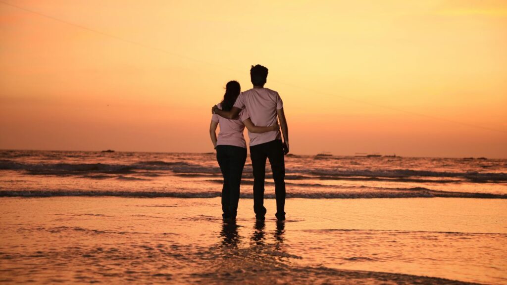 Couple walking on a beach, split finances as a couple UK using a joint account and shared budget system