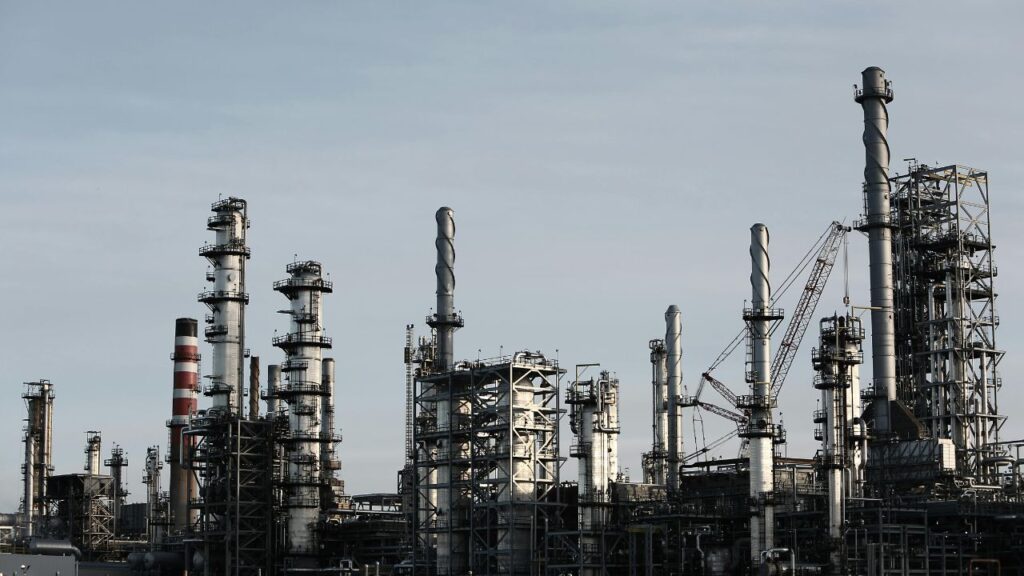 investing in energy stocks UK oil refinery at sunset