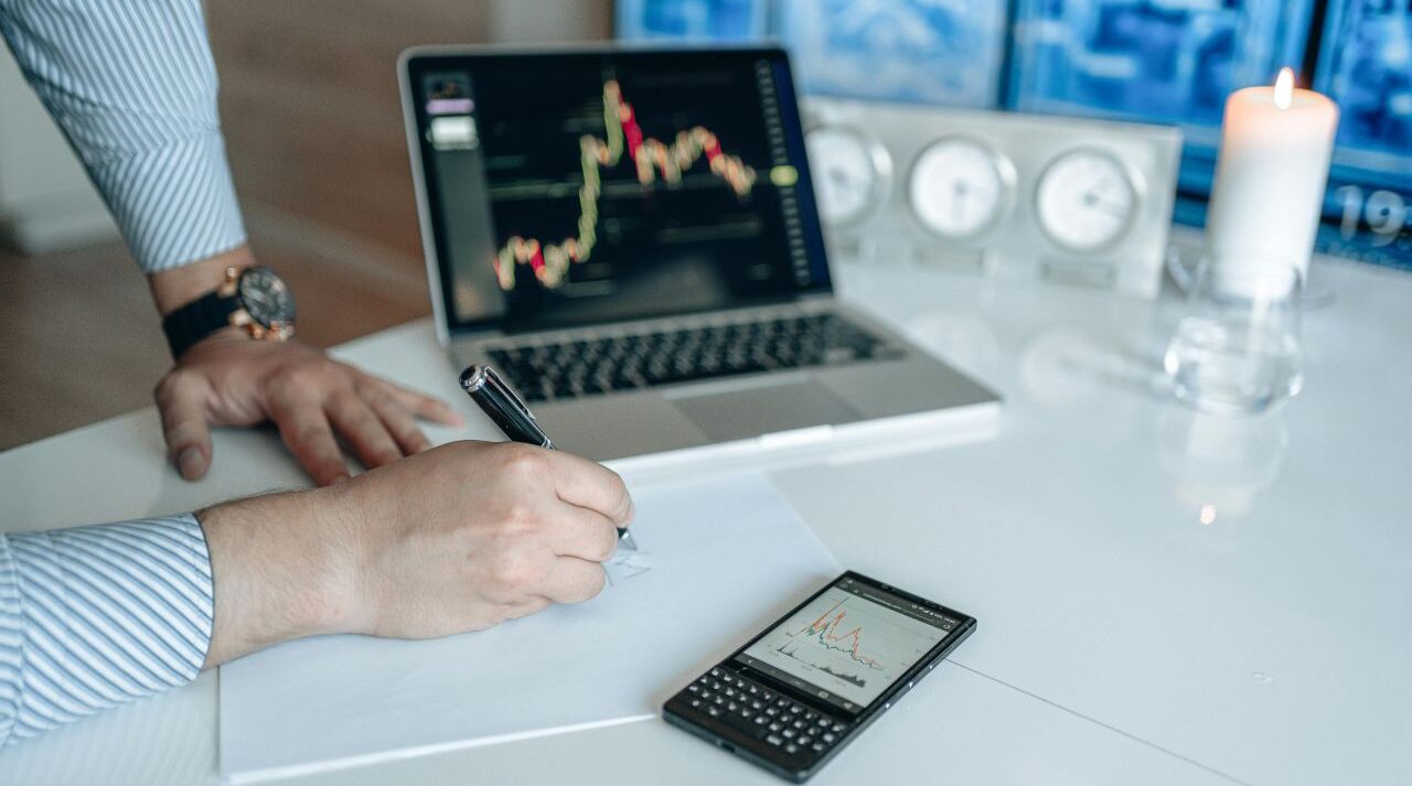 Man staring at stock market charts on laptop looking frustrated and uncertain